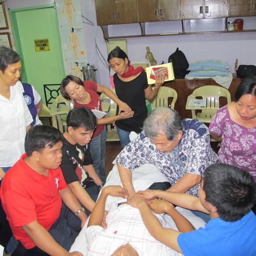 At the Jade Mountain CNT internal organs massage seminar for the visually impaired and blind and other students. I am demonstrating a manipulation while a couple of the blind students are holding my hands to follow the technique.