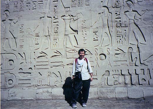 In the Temple of Karnak in front of the wall with hieroglyphs.